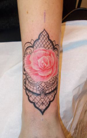 Tatouages d'une rose en couleur avec motif dentelle