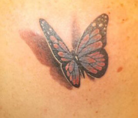 Tatouage en couleur d'un papillon posé sur l'épaule. Effet réaliste trompe l'œil.