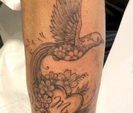 Tatouage d'un oiseau de style "fine art" ou "fine work" avec des détails très fins de fleurs.