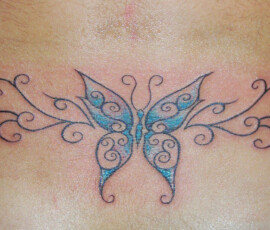Tatouage papillon dans le bas du dos avec arabesques