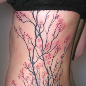 Tatouage fleurs de cerisier noir et rouge couvrant tout le coté.