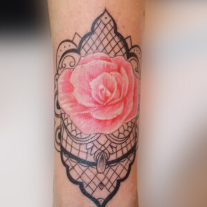 Tatouage rose et arabesque en dentelle sur le poignet