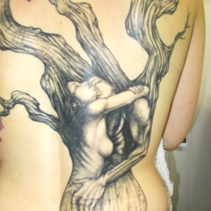 Tatouage d'arbre recouvrant tout le dos, avec des amoureux enlacés et des fleurs de cerisiers.