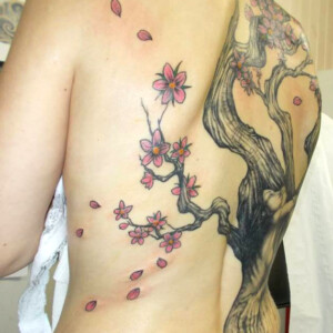 Tatouage d'arbre recouvrant tout le dos, avec des amoureux enlacés et des fleurs de cerisiers.