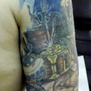 Tatouage sur le bras en couleur trésor et fond marin