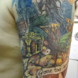 Tatouage sur le bras en couleur trésor et fond marin