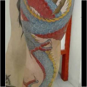Tatouage d'un dragon couleur s'enroulant autour de la jambe