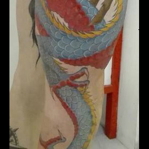 Tatouage d'un dragon couleur s'enroulant autour de la jambe