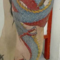 Tatouage d'un dragon couleur s'enroulant autour de la jambe