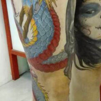 Tatouage d'un dragon couleur s'enroulant autour de la jambe