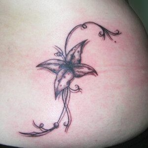 Tatouage petite fleur et arabesque dans le bas du dos
