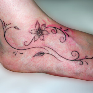 Tatouage fleur et arabesques sur le pied
