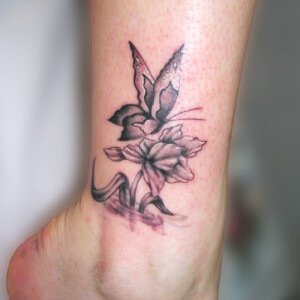 Tatouage fleur et papillon sur la cheville en noir et ombre