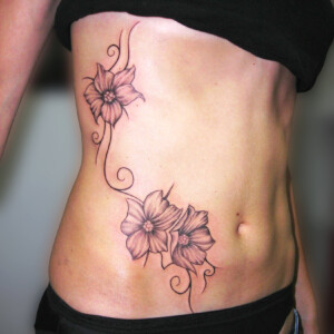 Tatouage fleur et arabesques noir sur le coté