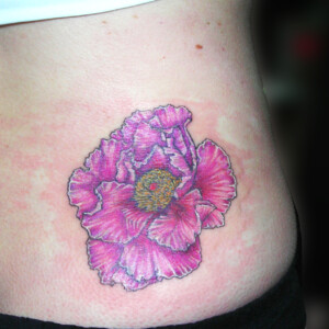 Tatouage d'une fleur de pivoine rose en couleur styles réaliste dans le bas du dos