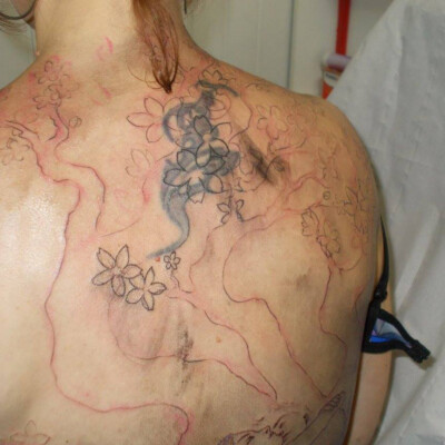 On ajoute des détails, des fleurs de cerisier... Les fleurs sont placées à des endroits stratégiques pour bien masquer l'ancien tatouage.