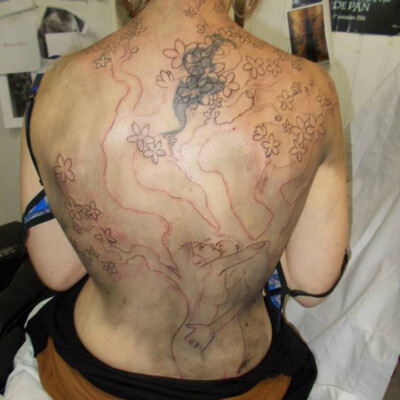 On ajoute des détails, des fleurs de cerisier... Les fleurs sont placées à des endroits stratégiques pour bien masquer l'ancien tatouage.