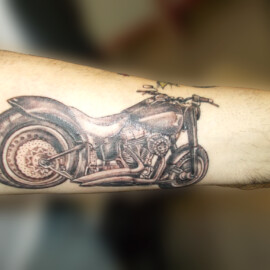 Tatouage moto sur le bras style réaliste en noir et ombres
