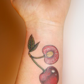 Tatouage mignon de cerises en couleur sur le poignet