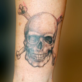 Tatouage tête de mort avec tibias croisés style réaliste en noir et ombrages