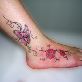 Tatouage fleur, papillon et arabesque sur le pied