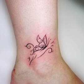 Tatouage papillon et arabesque sur le pied