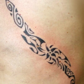 Tatouage de style polynésien qui vient souligner le coté du corps.