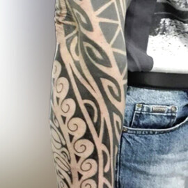 Tatouage de style tribal polynésien sur le bras complet